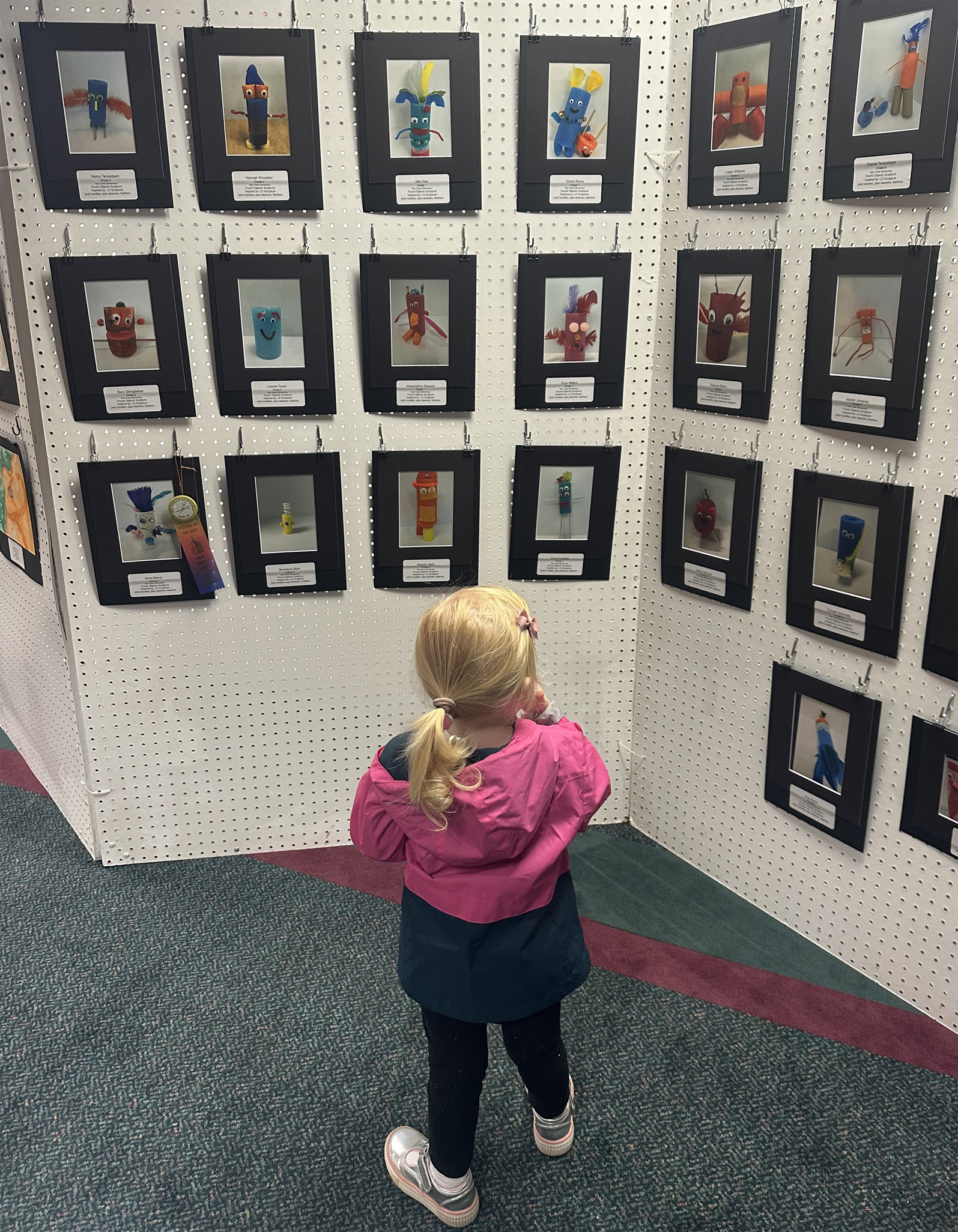 A young admirer looking at student artwork in the Youth Exhibit